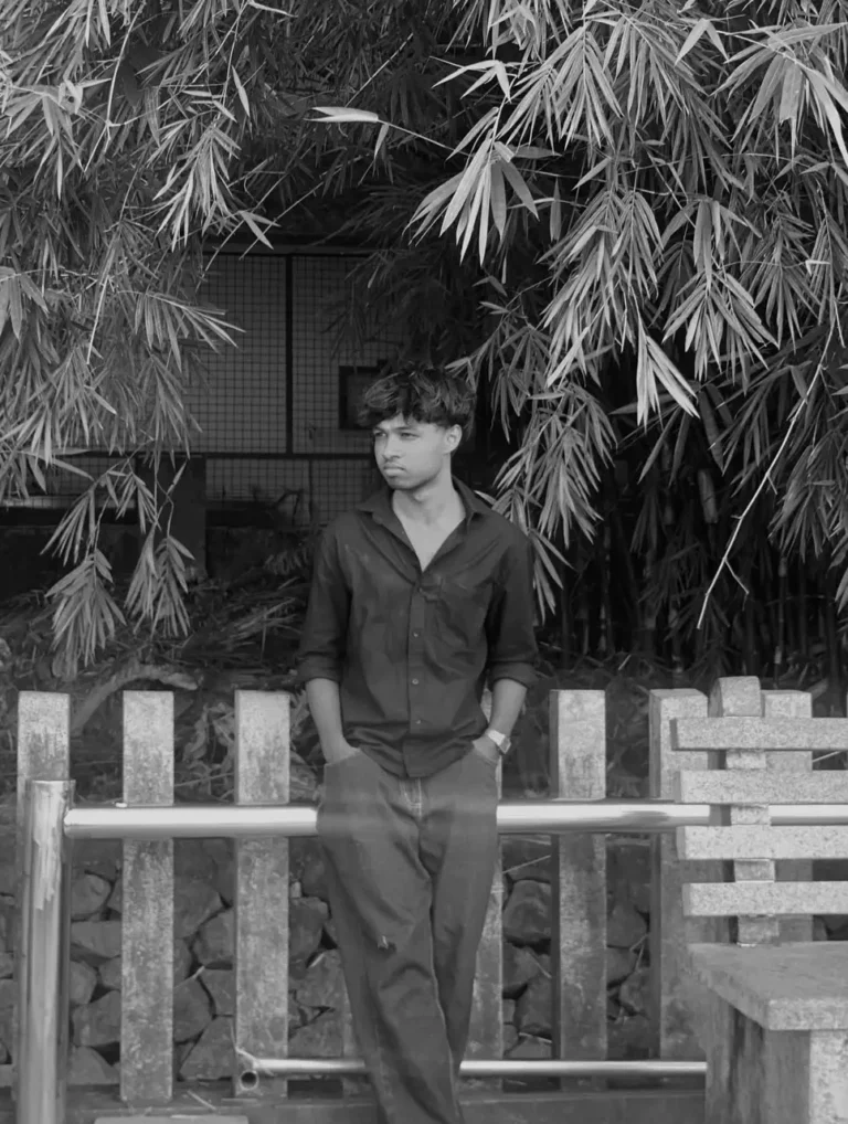 a man sitting on a wooden bench surrounded by a bamboo plants in black and white